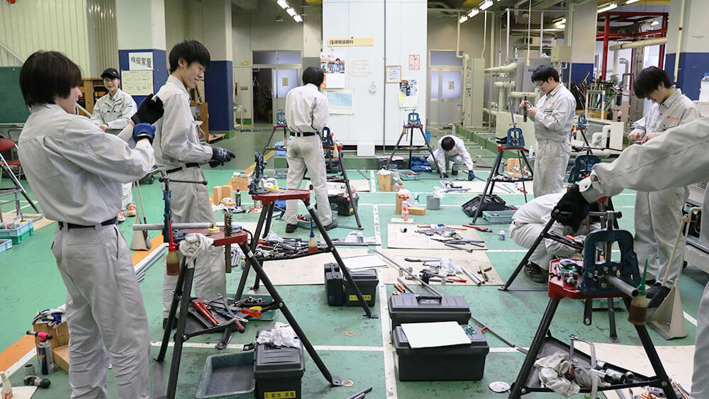 建築設備科の学生が実習場に集まって作業をしている写真